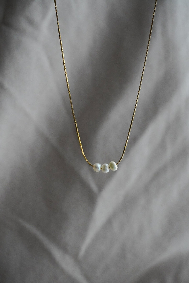 Collar lineal tres perlas de rio con chapa de oro.