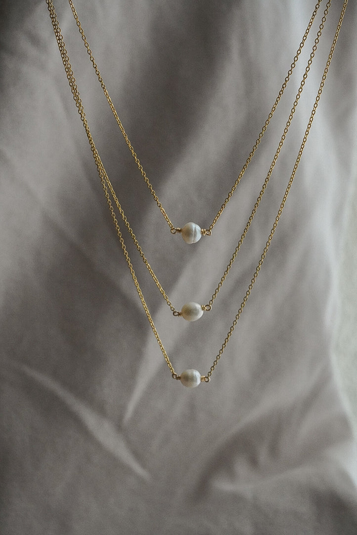 Collar triple perla de rio con chapa de oro.