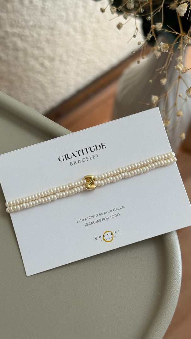 Pulsera doble con inicial de chapa de oro.